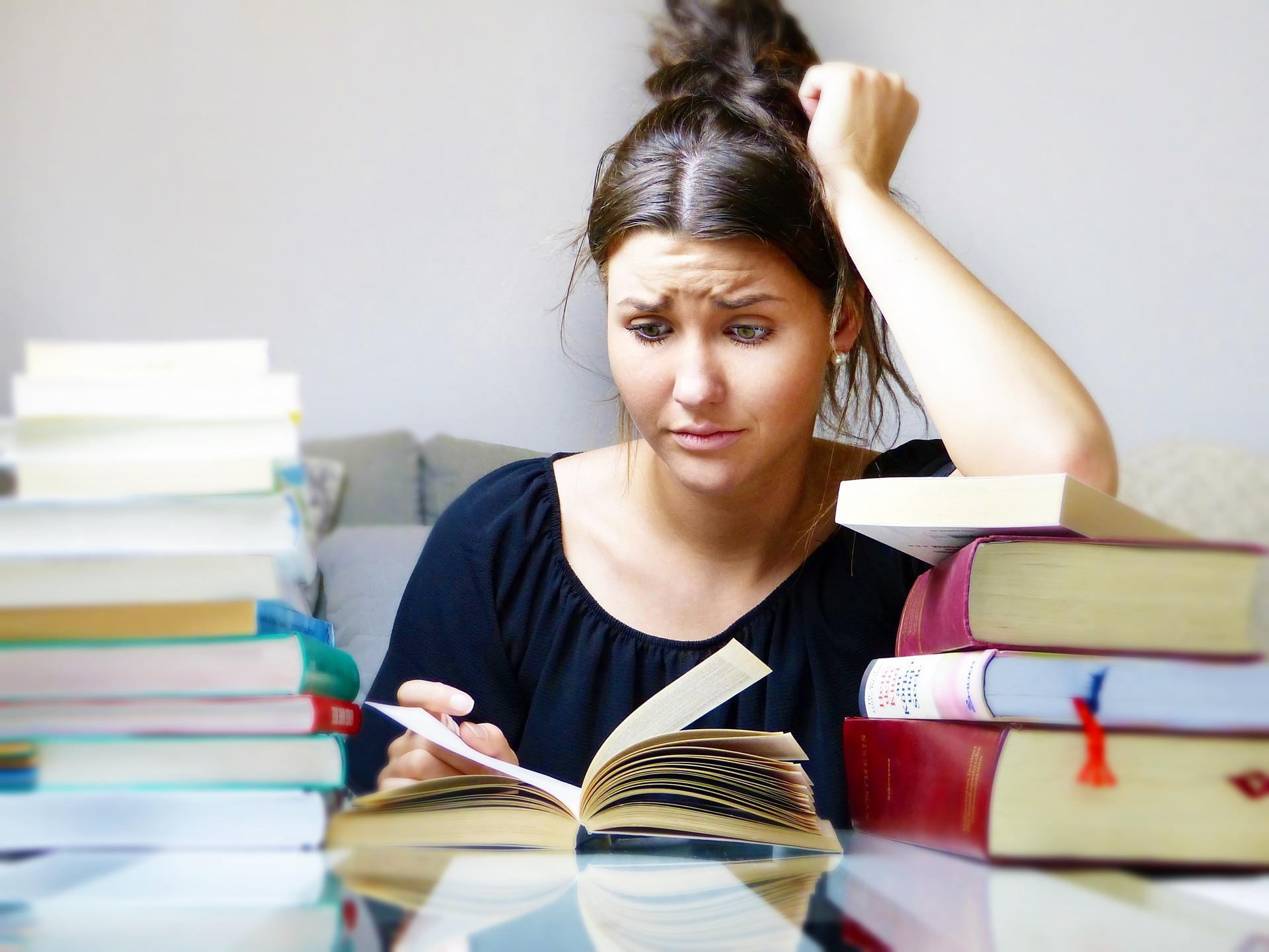 Frau schaut verzweifelt auf Bücher