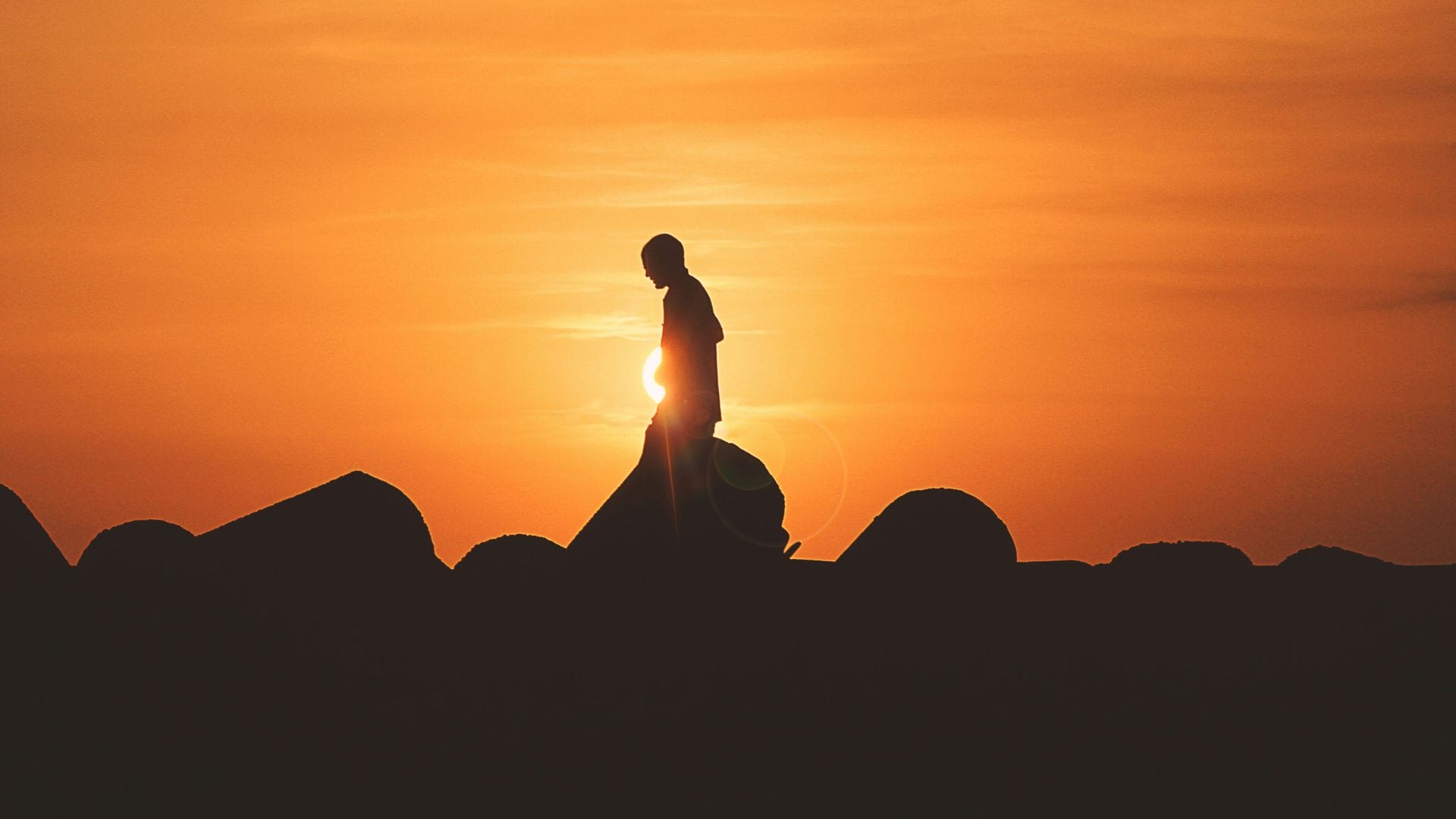 Mann geht im Hintergrund Sonnenuntergang