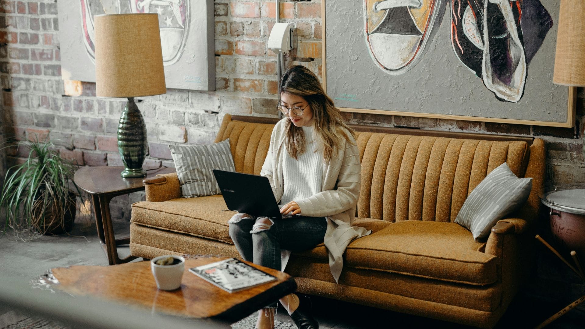 eine frau sitzt auf dem sofa und ist am laptop tätig